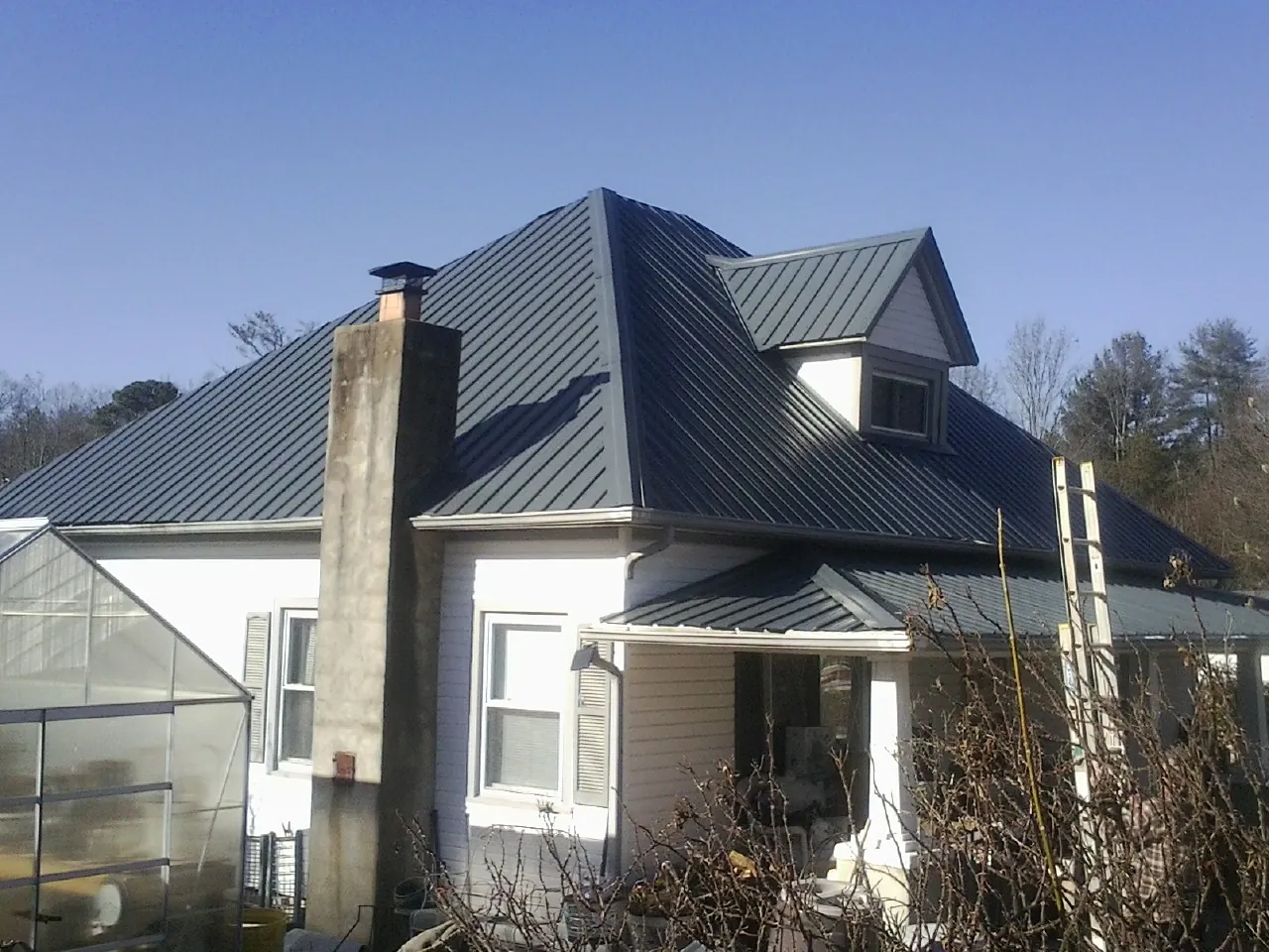 Dark blue standing seam metal roof on a white farmhouse with dormer — Slate & Tile Roof Repair by Roofing Brothers in Sabula