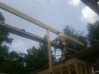 Carpenter setting a ridge beam over a new addition frame — Ice Dam Removal by Roofing Brothers in Sabula