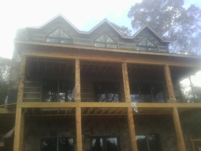 Dormers and porch framing on a large log home under construction — Roof Coating work by our crew in Sabula