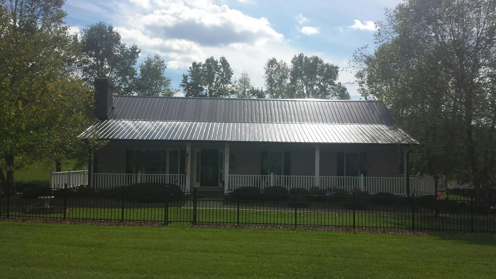Gray metal roof on a brick ranch with a full width front porch — Gutter Guard Installation work by our crew in Sabula