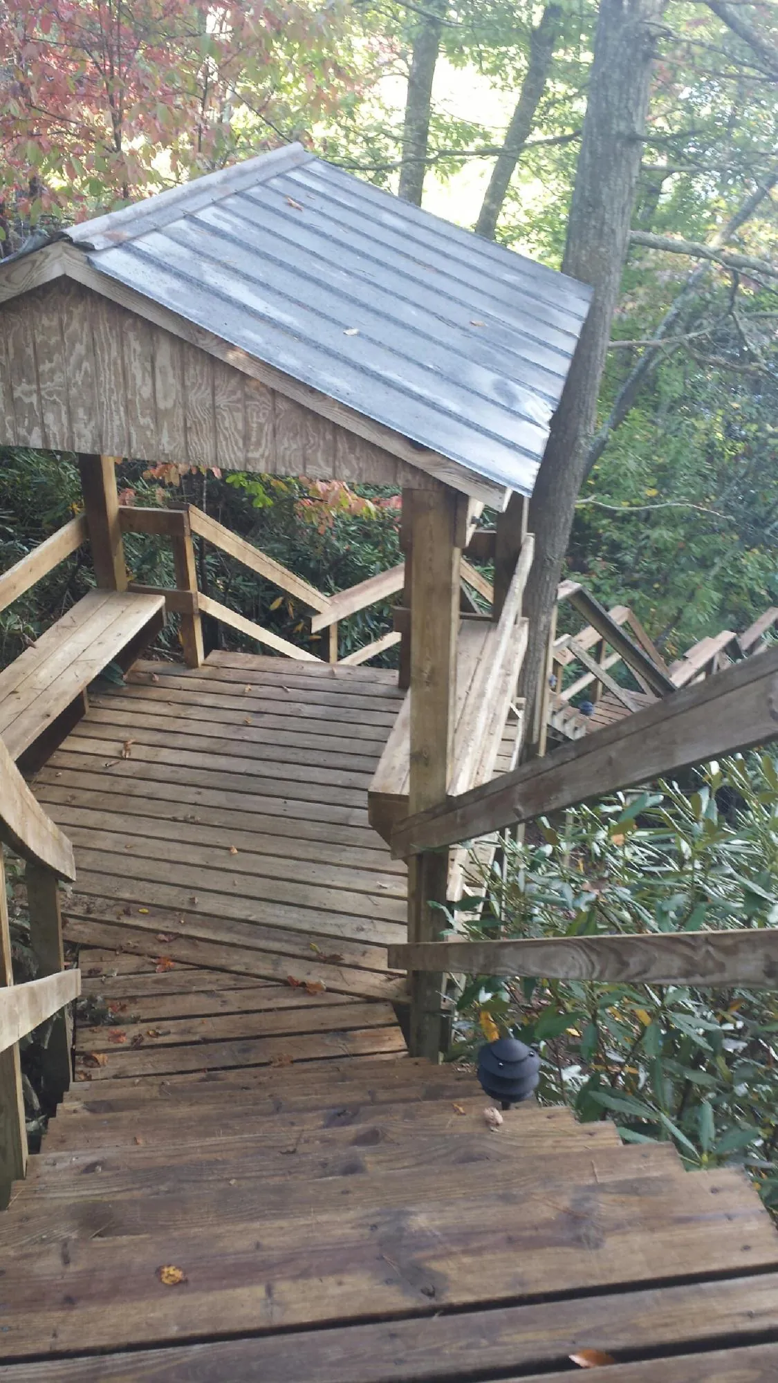 Metal roofed shelter over wooden steps on a wooded walkway — Skylight Repair & Installation work by our crew in Sabula