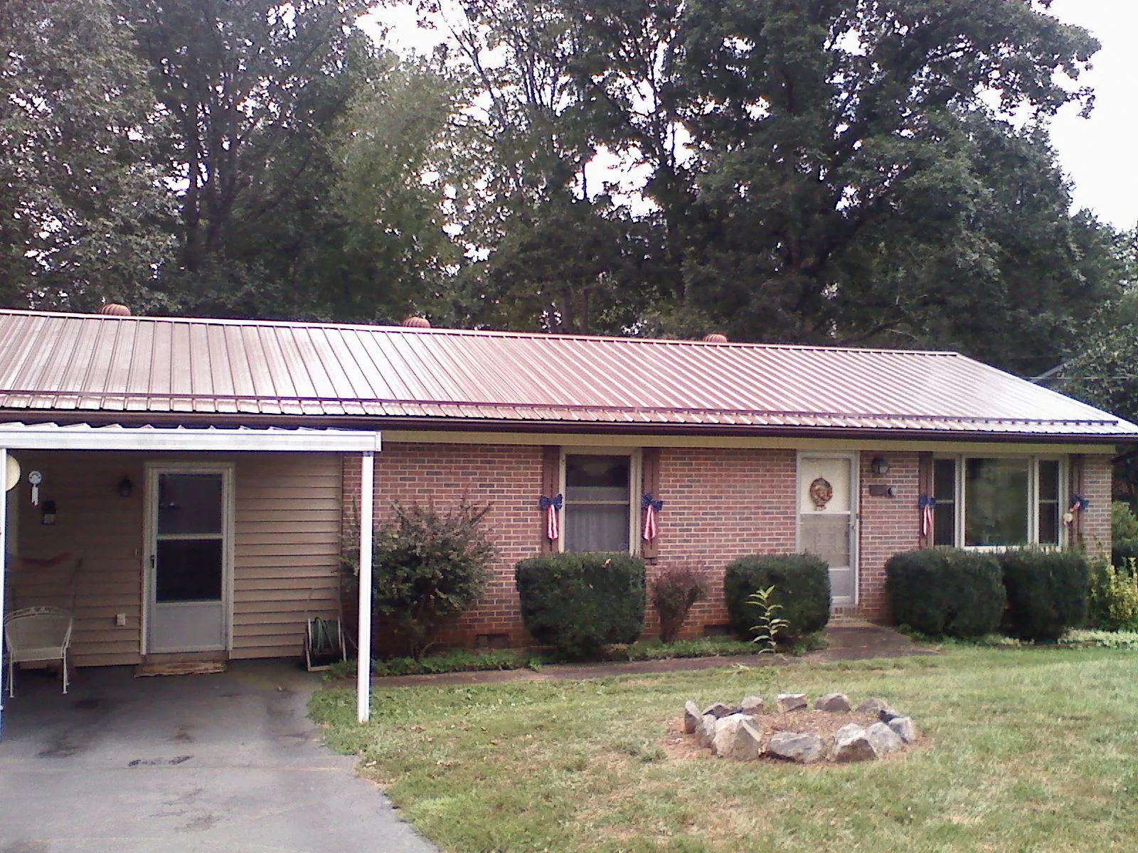 Bronze metal roof and carport on a brick ranch home — Roof Repair work by our crew in Sabula