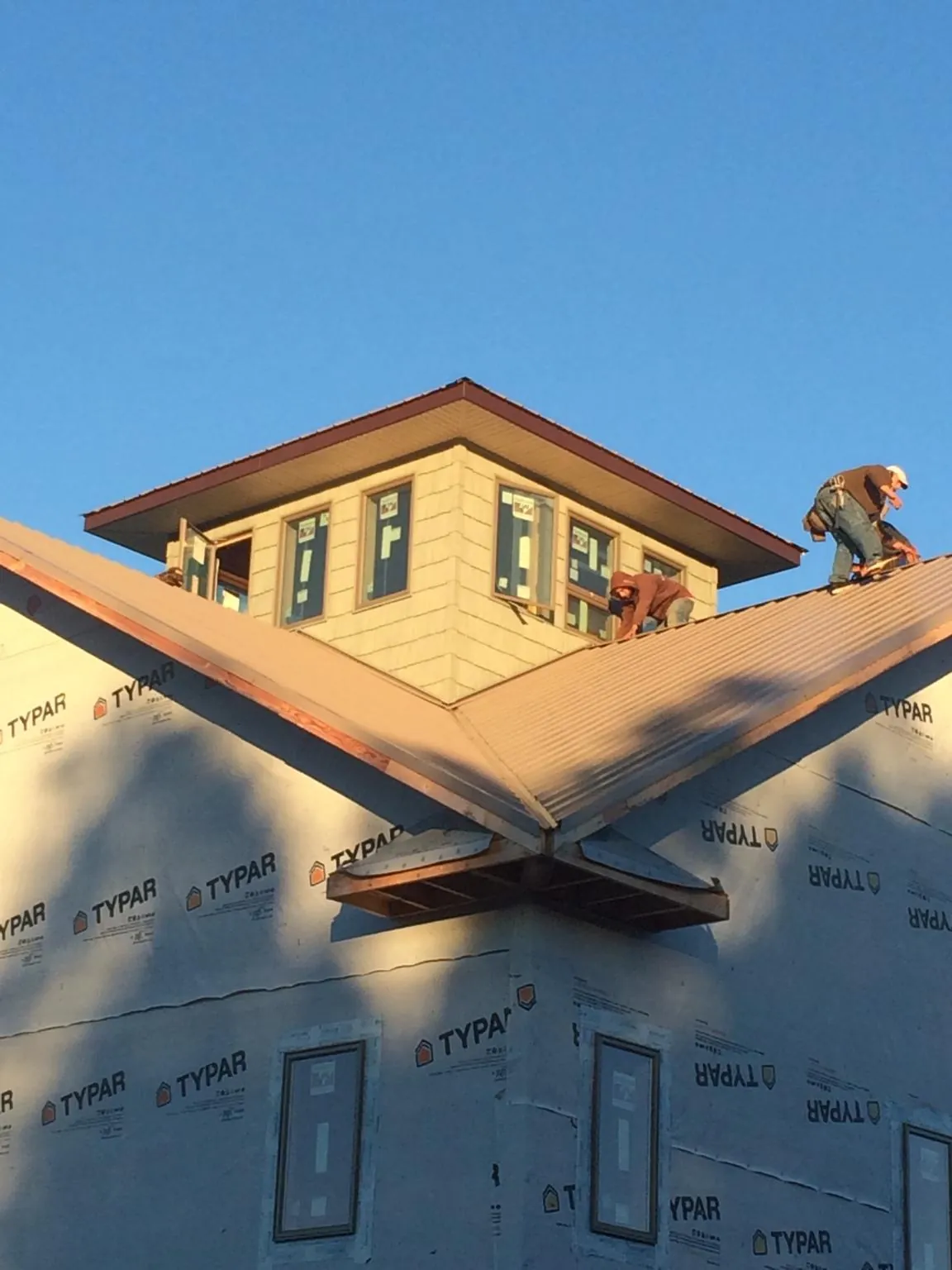 Roofers working around a rooftop cupola on a new metal roof at sunset — Roof Waterproofing in Sabula by Roofing Brothers
